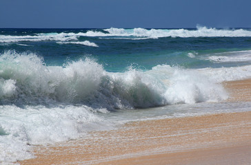Powerful ocean waves beat against the sandy shore