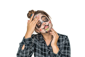 Young teenage girl with facial panda mask looking at camera isolated on white background. Cosmetic procedure. Beauty spa and cosmetology.