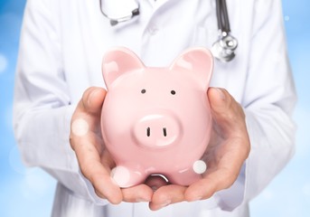 Doctor with Stethoscope Holding Piggy Bank close up