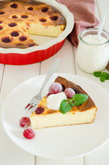 Diet healthy cottage cheese cake with cherries and sour cream on a white wooden background.