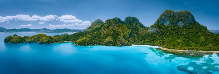 Fotobehang Luchtfoto drone panoramisch uitzicht op onbewoond tropisch eiland met ruige bergen, regenwoud jungle, zandstranden omgeven door blauwe oceaan © Igor Tichonow