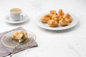 Homemade profiteroles with cream and coffee. Close-up.