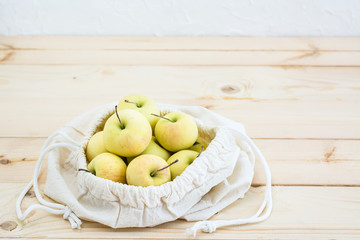 Canvas bag with ties with apples  on a natural wooden background. Zero Waste Concept