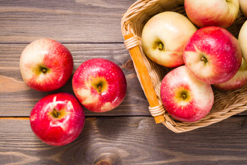 Ripe red apples and basket with apples on a wooden table. Top view
