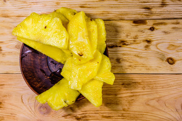 Ceramic plate with sliced pineapple on wooden table. Top view