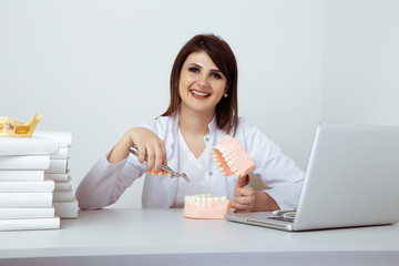 Woman dentist sitting at the table in office with dental staff isolated
