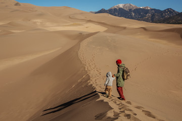 Fototapeta na wymiar A man with his son are hiking in desert