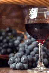 A glass of fragrant red wine and bunches of blue grapes