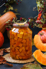 Pieces pumpkin in jar located on a dark background, harvesting vegetables for the winter, vertical orientation, closeup