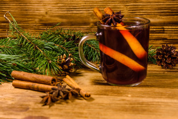Cup of mulled wine with cinnamon and fir tree branches on wooden table