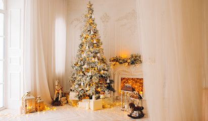 classical interior of a white room with a decorated fireplace, luxury Christmas tree, garlands, candles, lanterns, gifts. day. pink sofa pastel colors