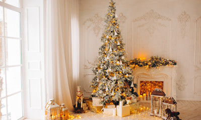 classical interior of a white room with a decorated fireplace, luxury Christmas tree, garlands, candles, lanterns, gifts. day. pink sofa pastel colors