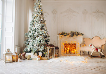 classical interior of a white room with a decorated fireplace, luxury Christmas tree, garlands, candles, lanterns, gifts. day. pink sofa pastel colors