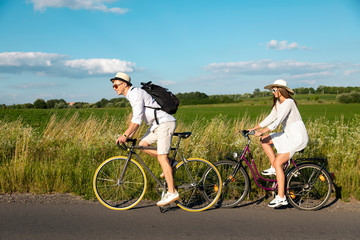 Young sporty couple riding bikes along a rural road
