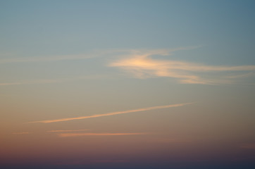 Blue sky with orange clouds and airplane track