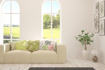 Stylish room in white color with sofa and summer landscape in window. Scandinavian interior design. 3D illustration