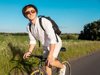 Young guy in white enjoys cycling through countryside
