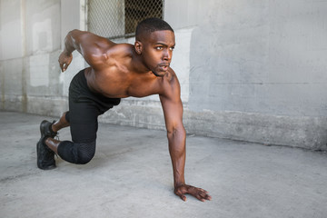 Shirtless male african american athlete training in urban city concrete background, sprinter, runner, jogger, muscular toned build training for race