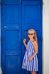 Fototapeta premium Adorable little girl at old street of typical greek traditional village