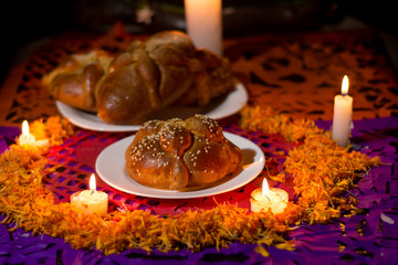 Pan de Muerto traditional recipe from Mexico, adorned with candles and cempasuchil flower petals,...