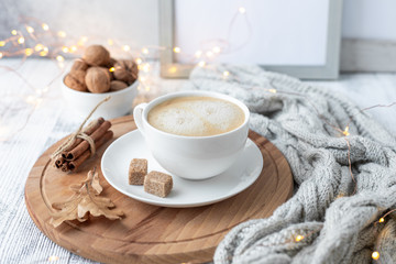 Cup of coffee, brown sugar, knitted scarf, garland. Autumn mood. Cozy autumn composition. Hygge concept. Soft focus