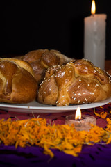 Bread of the dead on confetti and lighted candles with cempasuchil petals, Day of the Dead, Dark background