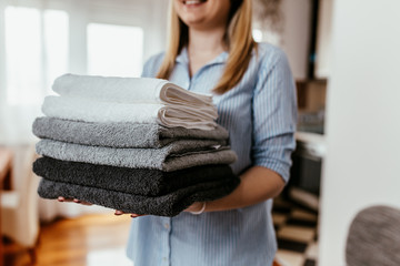 Young woman holding a pile of ironed clean towels.