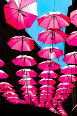 Fototapeta na wymiar Pinke Regenschirme in einer Straße in Frankreich
