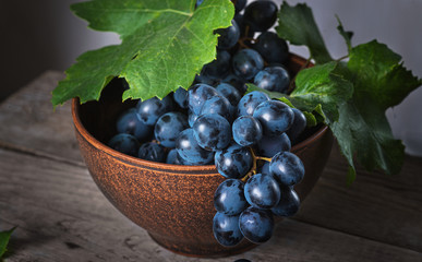  Fresh grapes in a clay plate on a wooden old table.