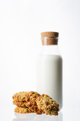 Bottle with milk on a white background. Glass bottle. Natural cork. White drink. Cow's milk. Homemade cookies on a white background. Pyramid of cookies. Cookies on top of each other.
