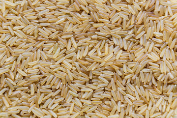 Uncooked raw long brown rice grains background, top view
