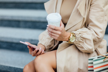 Close up photo, woman after shoppig in the city, shopping bags and coffee time, holding phone, woman shopaholic.
