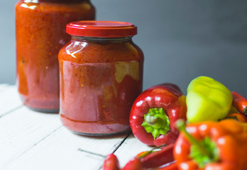 Fresh Ajvar made of tomatoes and paprika on the rustic wooden table.