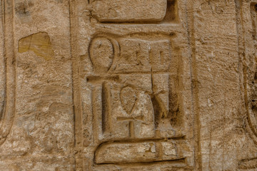 Egyptian ancient hieroglyphs on the stone wall. Closeup of the symbol of eternal life ankh