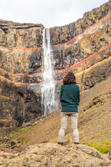 Hengifoss, Iceland »; August 2017: A young woman with a green jersey under the Hengifoss waterfall