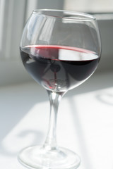 a glass of red wine on a white background with a play of shadows