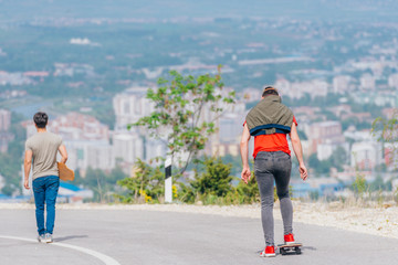 Tall athlete riding his longboard fast and steady downhill while wearing red t-shirt and black jeans.