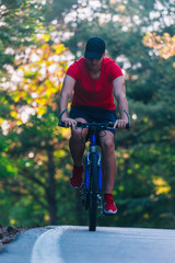 Tall handsome biker rides his bicycle on sunset in a lovely magical forest.