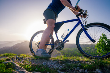 Fototapeta premium Close up photo from a mountain biker riding his bike ( bicycle) on rough rocky terrain on top of a mountain, wearing no safety equipment. Adrenalin junkie.