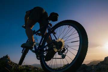 Silhouette of a mountain biker riding his mountain sportbike on top of a cliff ( hill). © qunica.com