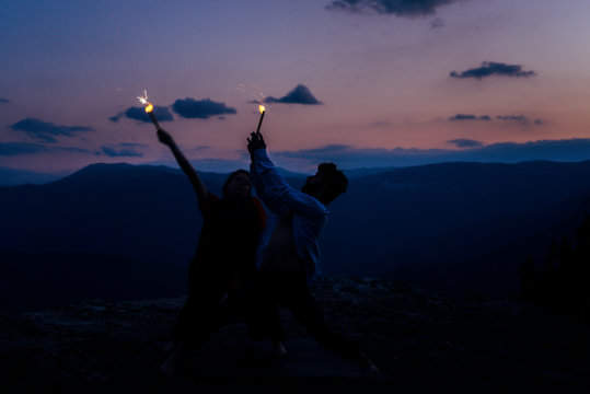 The two young silhouette people dancing hip hop on the mountain cliff, low key, dark image