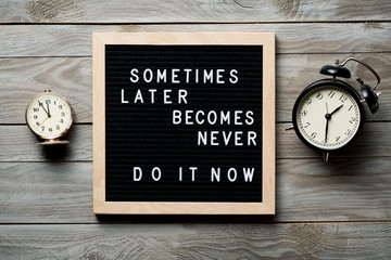 Inspirational motivational quote Sometimes later becomes never. Do it now words on a letter board on wooden background near vintage alarm clocks. Success and motivation concept. - obrazy, fototapety, plakaty