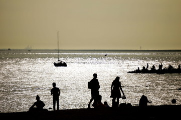 People on the shore. Yacht in silver light. Black and white contrast shot.