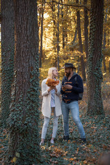 Romantic Autumn couple posing on nature background. Autumn outdoor portrait of beautiful happy girl and bearded man walking in park or forest. Young couple with autumnal mood.