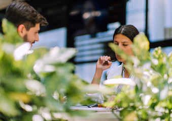 Obraz premium Happy young employees discussing data at meeting in bar
