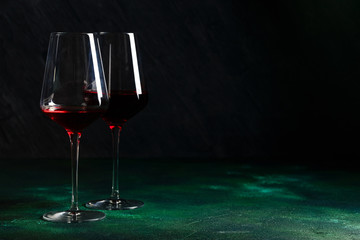 Bottle and glass of red wine on black background