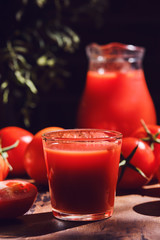 Tasty Tomato juice in a glass with ripe red tomatoes.