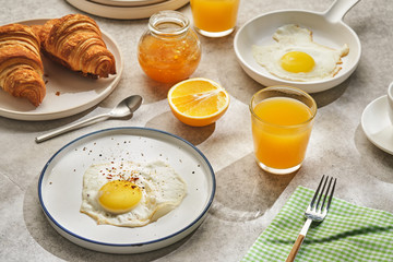 Continental breakfast. Fried eggs and sausage with croissants and orange juice.