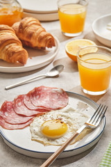Continental breakfast. Fried eggs and sausage with croissants and orange juice.