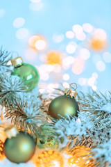 Christmas and New Year Holiday greeting card. Beautiful green ball, pine branches and a garland in the snow. Shallow depth of field. Toned image. Copy space. Blurred bokeh background.
